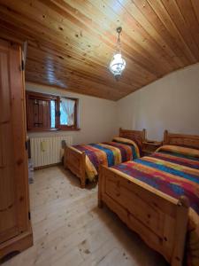 a bedroom with two beds and a wooden ceiling at Baita degli Alpini in Terminillo