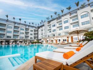 a pool with chaise lounge chairs in front of a hotel at TIME Marina North Coast in El Alamein
