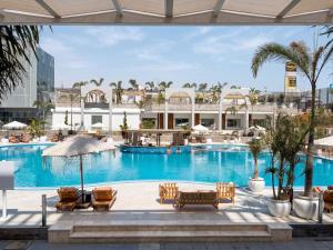a pool at a hotel with chairs and umbrellas at TIME Marina North Coast in El Alamein