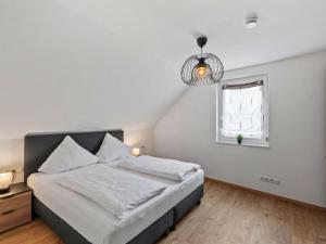 a bedroom with a bed and a window and a chandelier at Apartment Nina - 9 by Interhome in Endingen