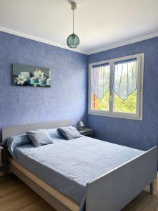 a blue bedroom with a bed and a window at Gîte Prat in Arette