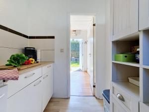 a kitchen with white cabinets and a table with vegetables at Apartment Gabi-1 by Interhome in Wiek auf Rügen