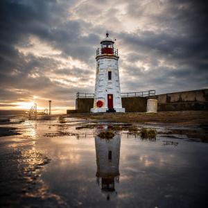 a lighthouse with its reflection in a body of water at Looking for long term rentals; huge discount. Caithness. in Lybster