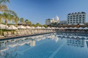 a swimming pool with chairs and umbrellas and a hotel at Adalya Elite Lara Hotel - Ultra All Inclusive in Lara