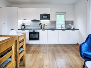 a kitchen with white cabinets and a blue chair at Chalet Golden View by Interhome in Janske Lazne