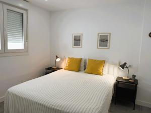 a bedroom with a bed with yellow pillows and a window at Luxury beach penthouse with Jacuzzi in Fuengirola