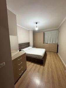 a bedroom with a large bed and a wooden floor at Apartament Yzberish in Tirane