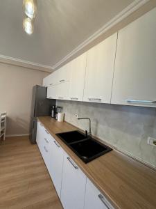a kitchen with white cabinets and a sink at Apartament Yzberish in Tirane