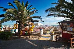una playa con una palmera y un parque infantil en Hotel Acrux, en Gabicce Mare