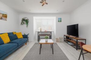 a living room with a blue couch and a tv at Driftwood by Grandeur Property in Bournemouth