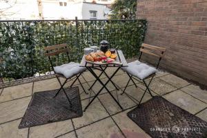a table with a plate of fruit and two chairs at Driftwood by Grandeur Property in Bournemouth
