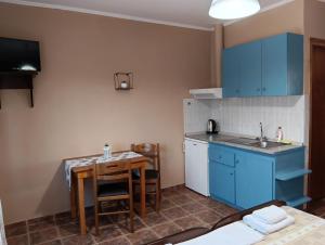 a kitchen with blue cabinets and a small table at Ξενώνας Αντωνία in Kato Loutraki