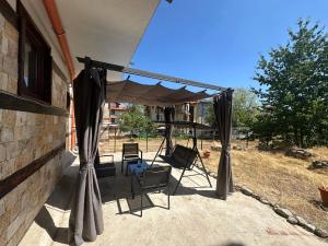 a patio with a canopy and chairs under a house at Borealis Apartment in Bansko