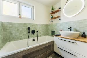a bathroom with a white tub and a sink at Townhouse Am Kurpark - Ferienhaus, 2 Schlafzimmer, Arcade, Wallbox, inklusive Wäsche in Braunlage
