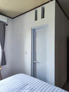 a bedroom with a white bed and a door at MD Amed Guest House in Amed