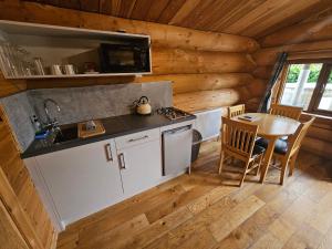 a kitchen with a sink and a table in a cabin at Mountain Edge Resort Lodge 2 with Hot Tub in Church Stretton