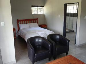 a bedroom with a bed and a leather chair at The View on Vaal Resort in Sasolburg
