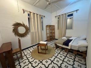 a bedroom with a bed and a chair and a mirror at Brown & White House in Paje