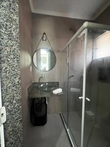a bathroom with a shower and a sink and a mirror at Recanto Praia do Sargi in Uruçuca