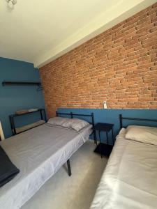 two beds in a room with a brick wall at Apartamento Parque Trianon Exclusive in Araçatuba +49 photos