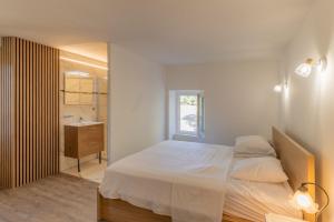 a bedroom with a bed and a bathroom with a sink at "Chez Jean" à Ruoms in Ruoms