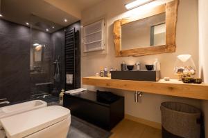 a bathroom with a toilet and a sink and a mirror at Luxury Lodges by Grand Hotel Sitea in Sestriere