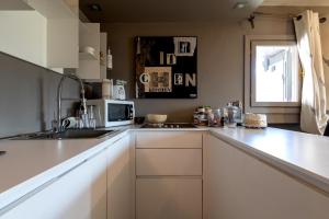 a kitchen with white cabinets and a sink and a microwave at Luxury Lodges by Grand Hotel Sitea in Sestriere