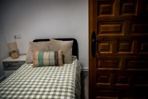 a bed with a checkered blanket next to a door at El Rincón del Silencio in Entrala +3 photos