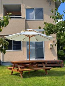 a picnic table with an umbrella in front of a house at Yamamori House in Hakuba