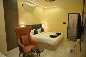 a bedroom with a bed and a chair and a mirror at Hotel Bliss Kashi in Kakarmatha