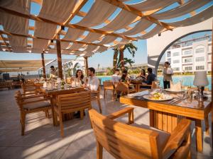 a restaurant with wooden tables and chairs and a pool at TIME Marina North Coast in El Alamein