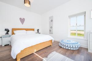 a white bedroom with a large bed and a window at Ramsey View in Solva