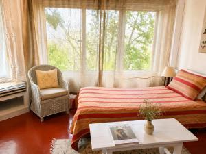 a bedroom with a bed and a chair and a window at Kumaon Cottage, Nainital - AM Hotel Kollection in Nainital