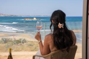 a woman sitting in a chair holding a glass of wine at Akanthus Pirgos Bay in Malia