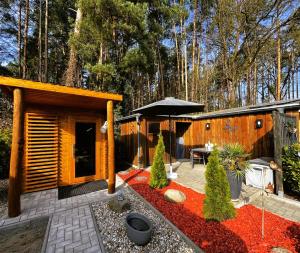 a backyard with a cabin with a table and an umbrella at Wellness Ferienhaus Garden in Michendorf