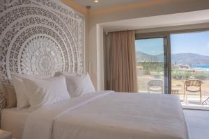 a bedroom with a large bed and a large window at Akanthus Pirgos Bay in Malia