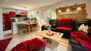 a living room with a black leather couch and a kitchen at Wellness Ferienhaus Garden in Michendorf