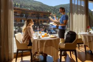 a man serving a woman at a table in a restaurant at Hotel Splendid in Madonna di Campiglio +159 photos