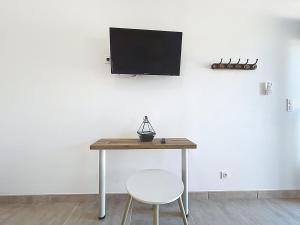 a table with a chair and a tv on a wall at Studio avec terrasse en rez de chaussée in Lapalme +3 photos