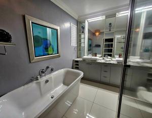 a white bathroom with a tub and two sinks at 62 Camarque Umdloti Beachfront in Umdloti