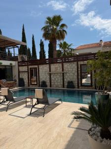 a swimming pool with two chairs and a house at The Alaçatı Ariel Hotel in Çeşme