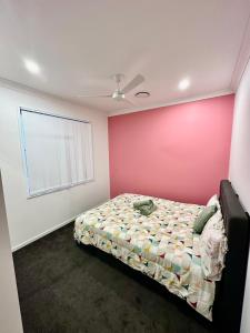 a bedroom with a bed and a pink wall at Noble place in Loganlea in Loganlea