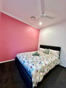 a bedroom with a bed with a pink wall at Noble place in Loganlea in Loganlea +2 photos