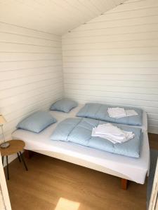 a bed in a small room with blue pillows at Rudbøl Naturcamping in Højer