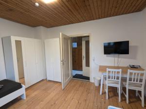 a living room with a table and chairs and a flat screen tv at Härtsfeldwohnungen in Neresheim