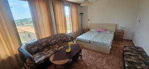 a living room with a couch and a bed and a table at Атлас in Byala