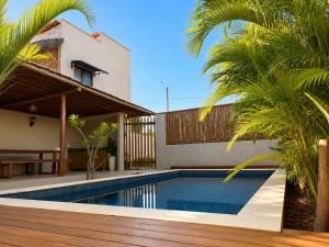 a swimming pool in front of a house with palm trees at Villa Vinci Flat in São Miguel do Gostoso
