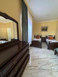 a bedroom with two beds and a dresser with a mirror at Cottage Shara - შარა in Ureki +14 photos