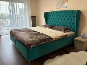 un letto con testiera verde in una camera da letto di Esterhazy Apartman a Galanta