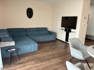 un soggiorno con un divano blu e una TV di Esterhazy Apartman a Galanta